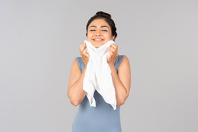 Улыбающаяся молодая индийская женщина вытирает лицо полотенцем