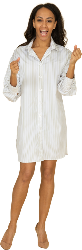 Vista frontal de uma jovem mulher de pele escura gritando em um vestido branco cerrando os punhos