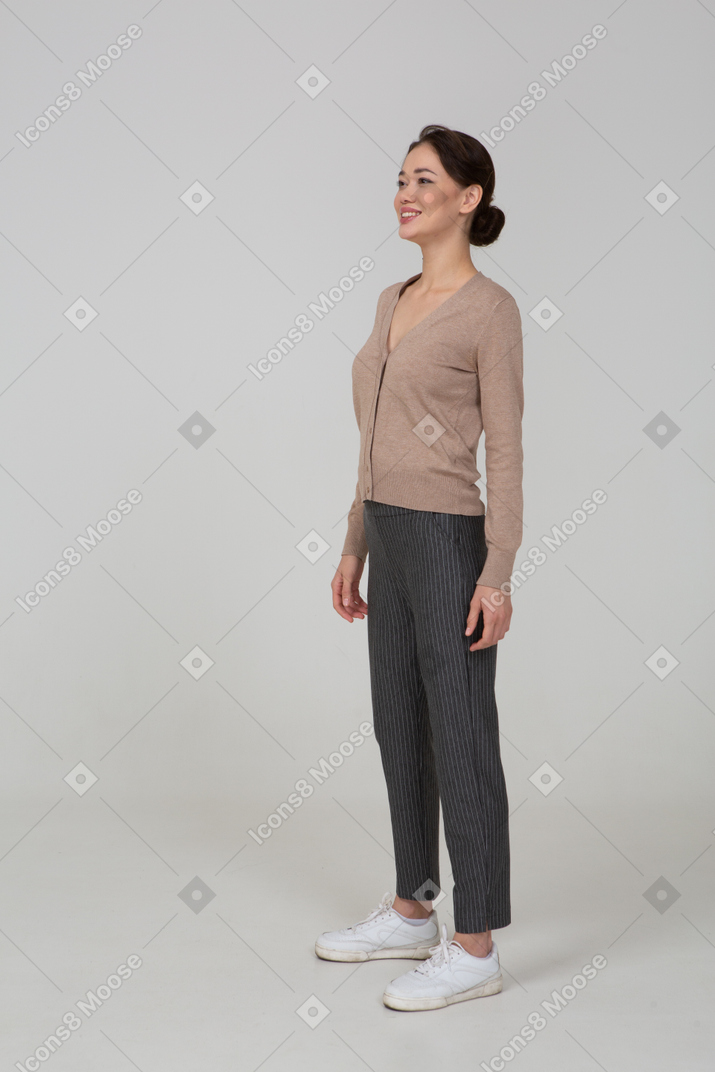 Vista di tre quarti di una donna sorridente in pullover e pantaloni