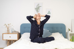 ベッドで寝ているパジャマ姿のストレッチの若い女性の正面図