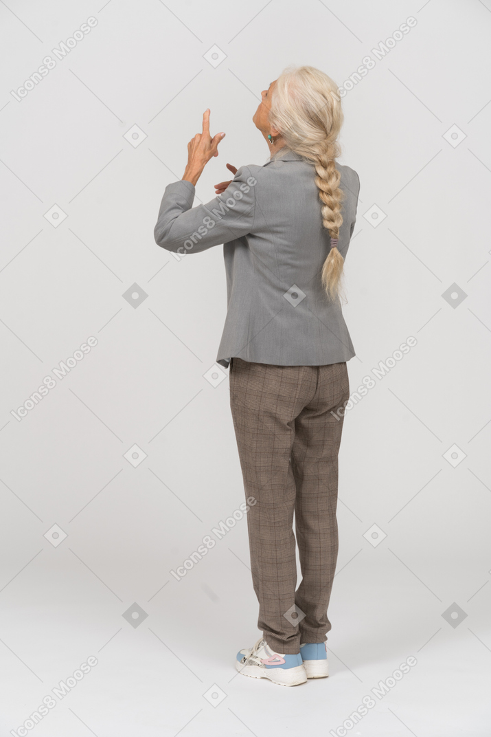Rückansicht einer alten dame im anzug, die mit den fingern zeigt
