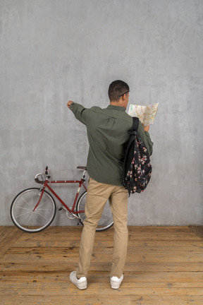 Back view of a man with a backpack and a map showing directions