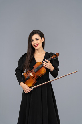 Close-up de uma jovem alegre de vestido preto segurando o violino