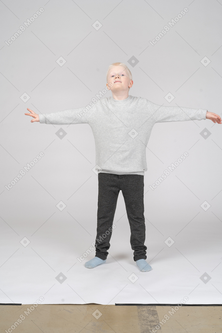 Vista frontal de um menino de pé em uma pose de estrela