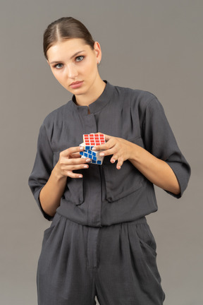 ルービックキューブを保持しているジャンプスーツの若い女性の正面図