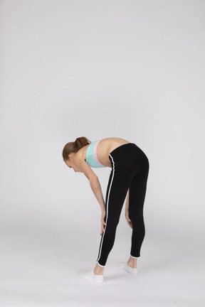 Side view of a teen girl in sportswear squatting and putting hands on hips