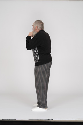 Rear view of old man with fingers in mouth