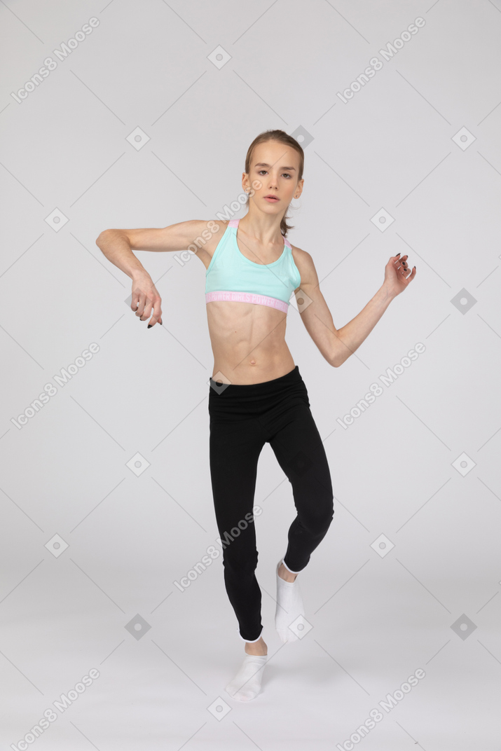 Front view of a teen girl in sportswear stepping forward and gesticulating