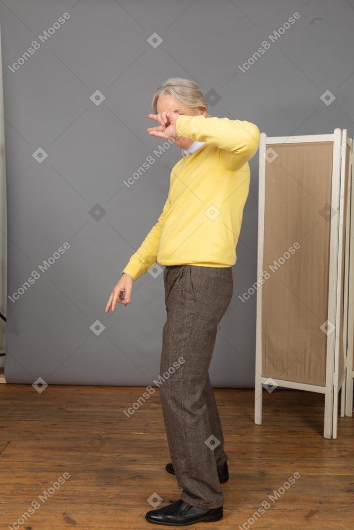 Three-quarter view of a cool dancing old man hiding his face