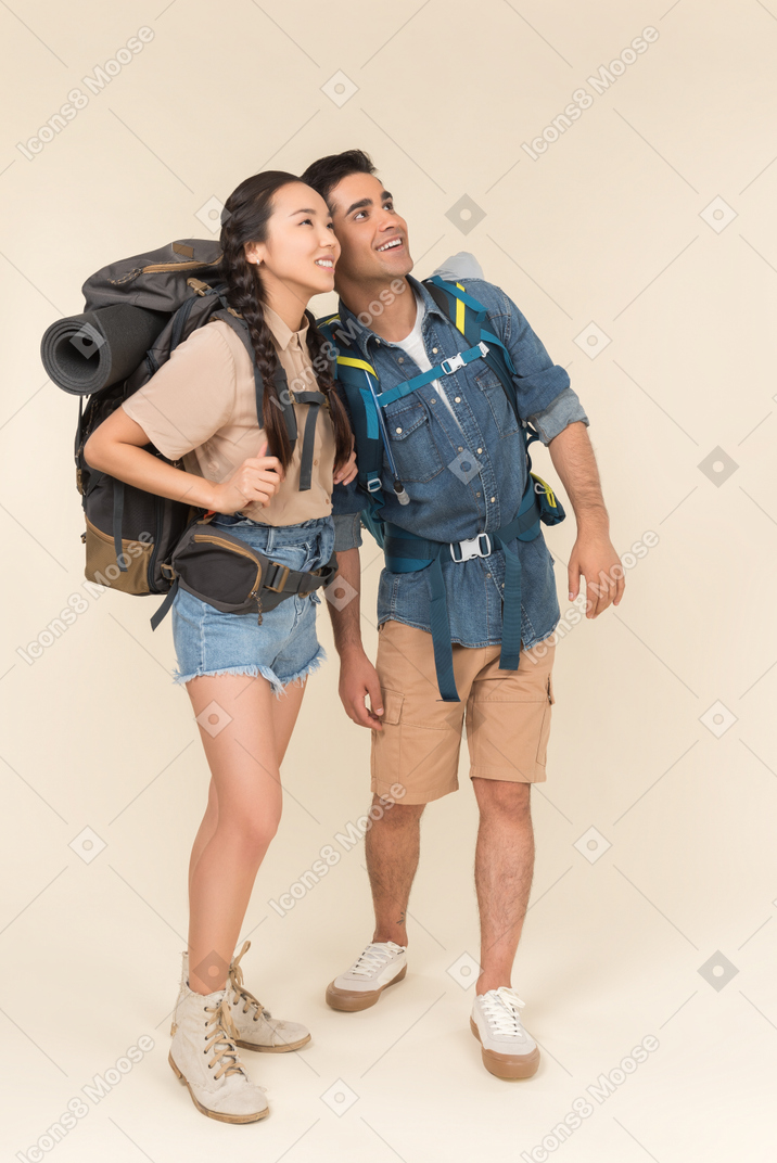 Joven pareja interracial de excursionistas mirando atentamente