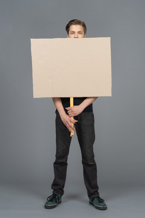 Serious young man standing with a blank  poster