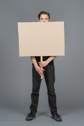 Joven serio de pie con un cartel en blanco