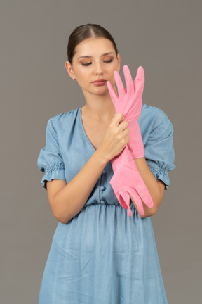 Front view of a young woman putting on a latex glove