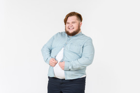 Giovane uomo in sovrappeso, cercando di chiudere la camicia su di lui
