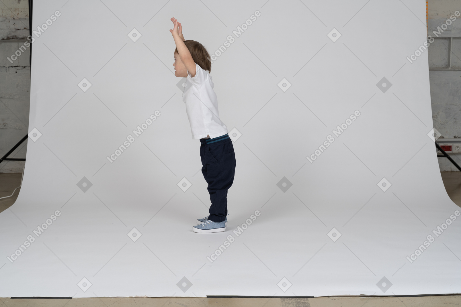 Vista laterale di un ragazzino in piedi con le braccia alzate