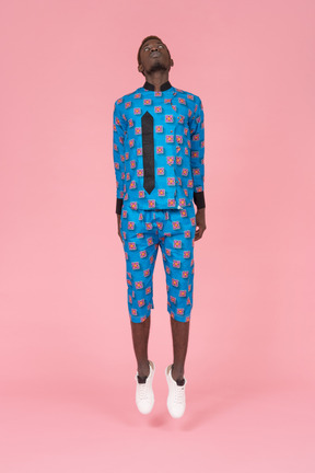 Homme noir en pyjama bleu sautant sur fond rose