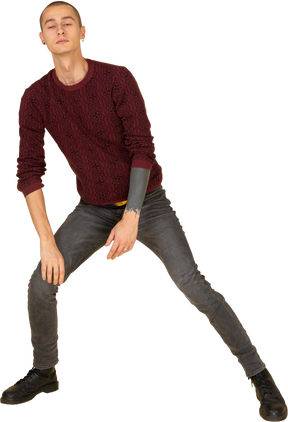 Front view of a young man in red pullover stretching his leg