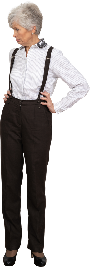 Front view of a pouting old lady in office clothing putting hands on hips