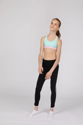 Vista lateral de una jovencita en ropa deportiva levantando la mano y argumentando