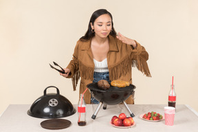 Joven asiática haciendo y oliendo barbacoa