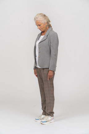 Vista lateral de una anciana en traje mirando hacia abajo