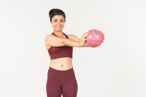 Junge indische frau in sporstwear holding ball