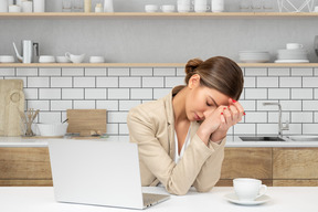 A woman is sitting at a table with a laptop in front of her