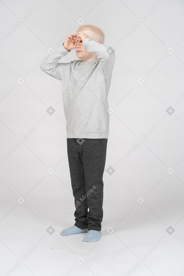 Little boy looking at something through imaginary binoculars