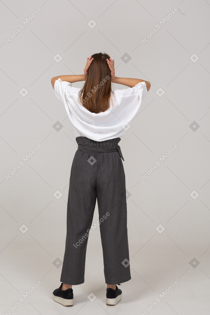 Back view of a young lady in office clothing touching her ears