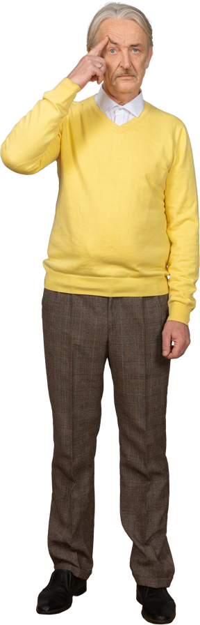 Front view of an old thoughtful man wearing yellow pullover and touching forehead