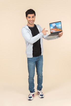 Young caucasian man presenting laptop