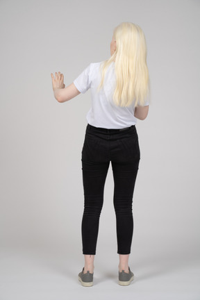 Back view of a standing young lady holding up her arm