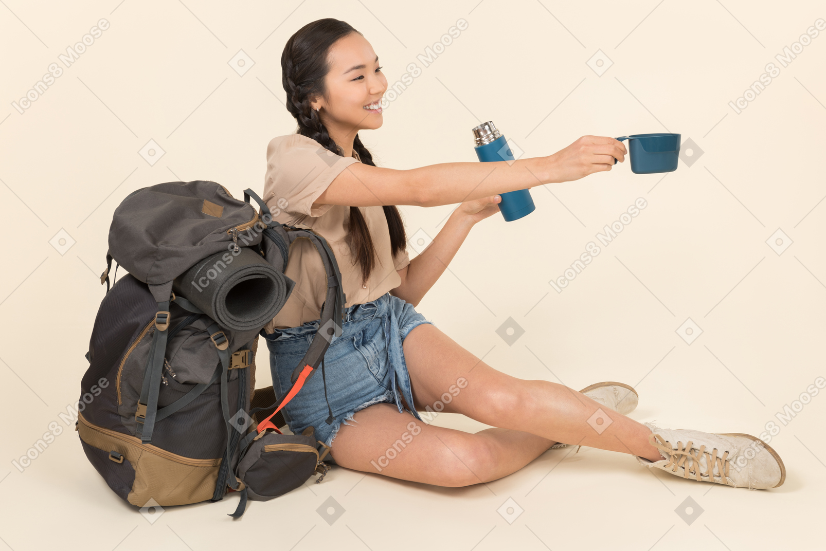Jovem mulher asiática sentado perto de mochila e manuseio de garrafa térmica