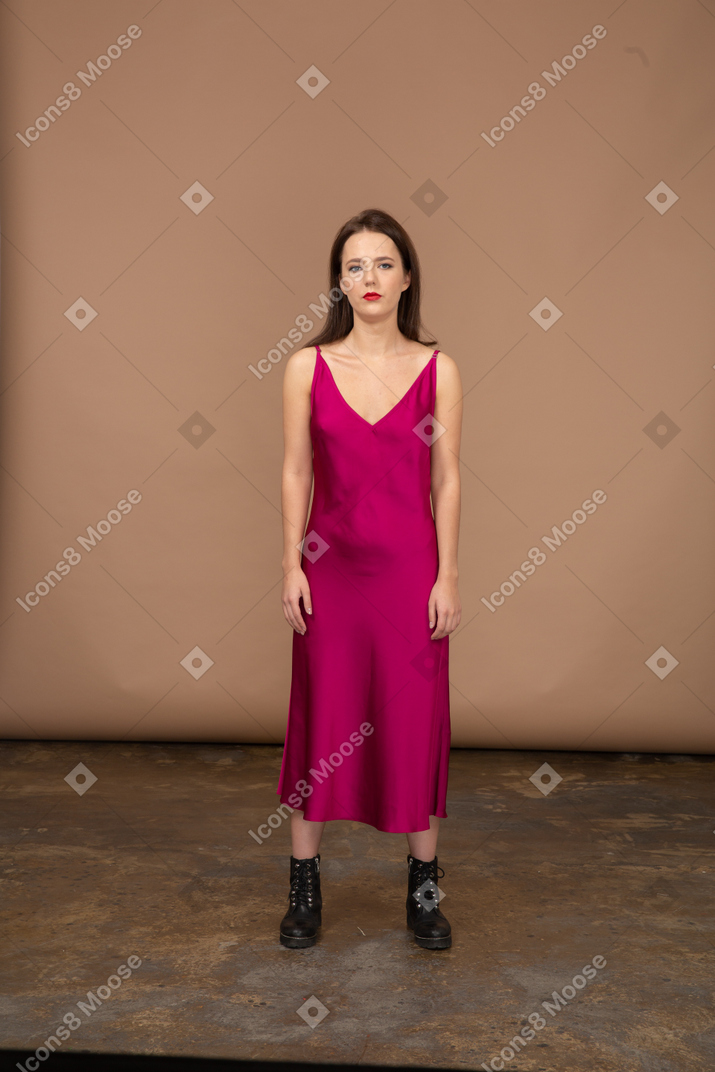 カメラを見て美しい赤いドレスを着た若い女性の正面図