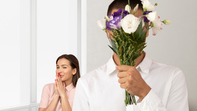 A man is holding a bouquet of flowers in front of a woman