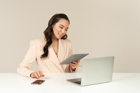 Азиатский женский офисный работник, глядя на планшет