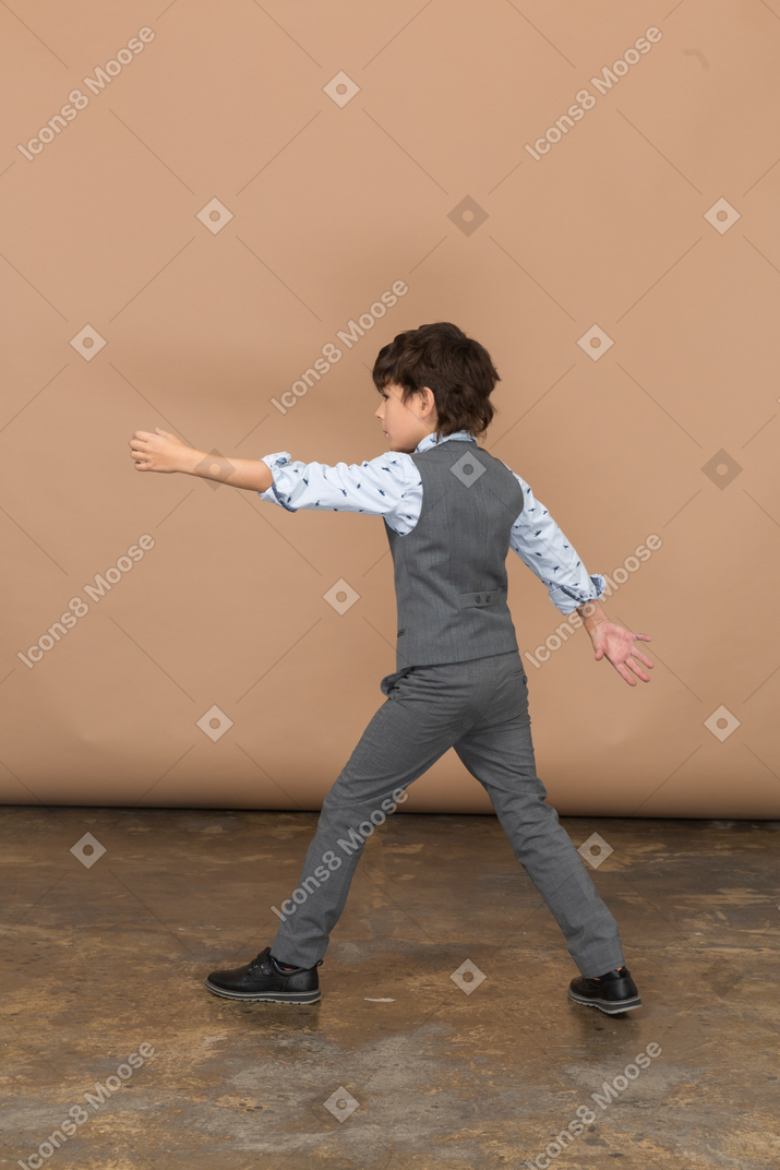 Vista lateral de um menino bonito de terno andando