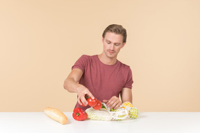 Young guy putting fruits and vegetables into a string bag