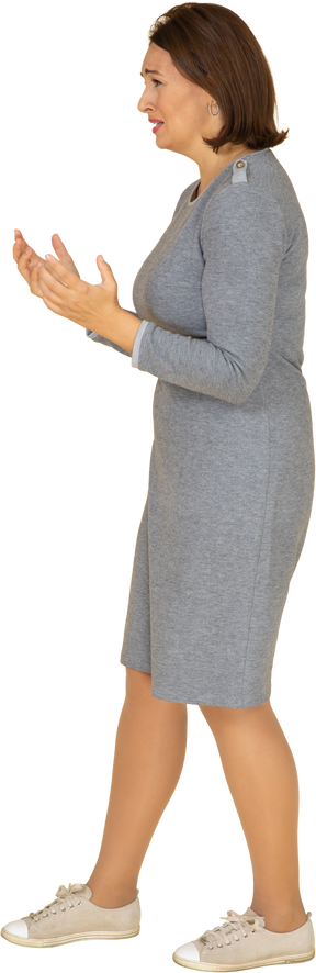Vista lateral de uma mulher triste em um vestido cinza gesticulando