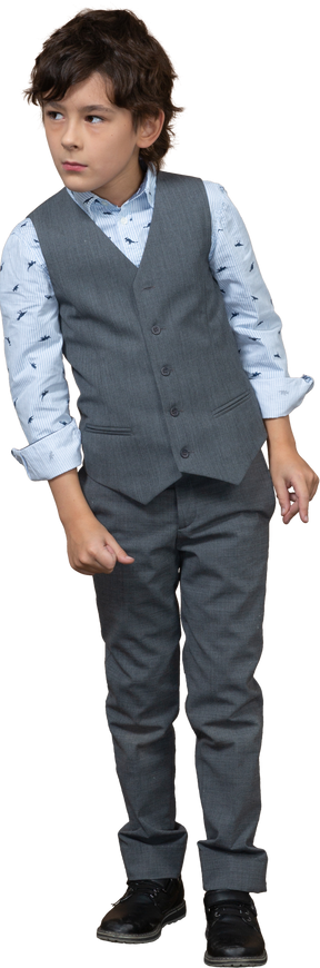 興味を持って何かを見ている灰色のスーツを着たかわいい男の子の正面図
