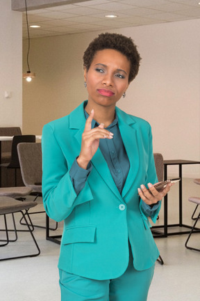 A woman in a turquoise suit holding a cell phone