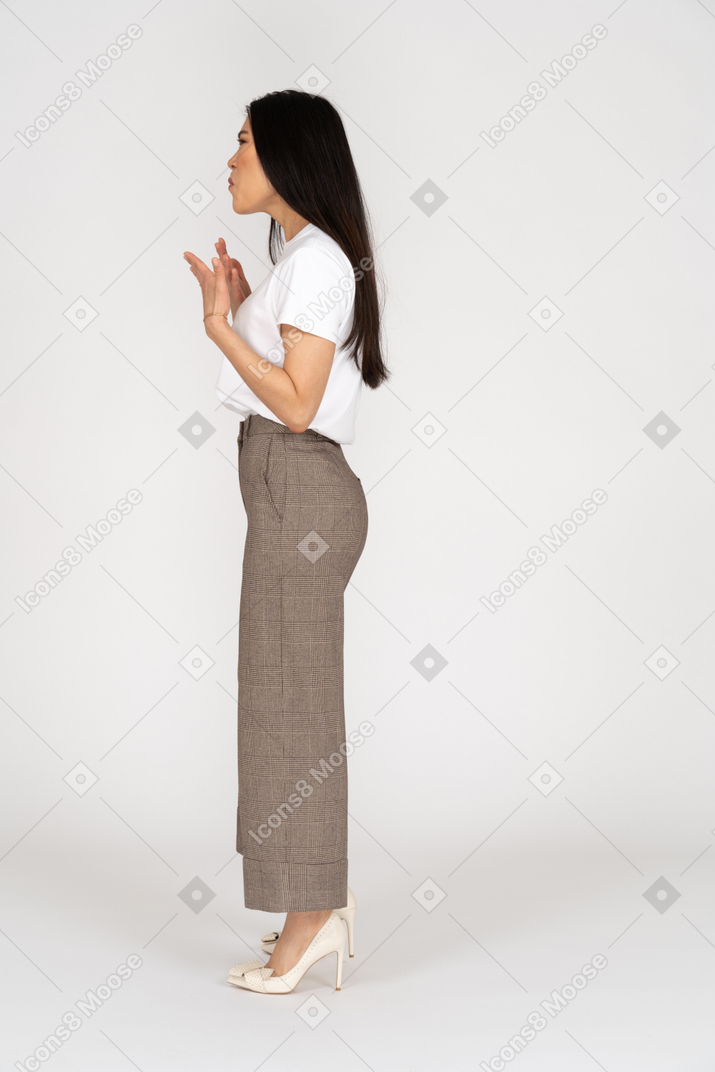 Vista laterale di una giovane donna gesticolante scontenta in calzoni e maglietta