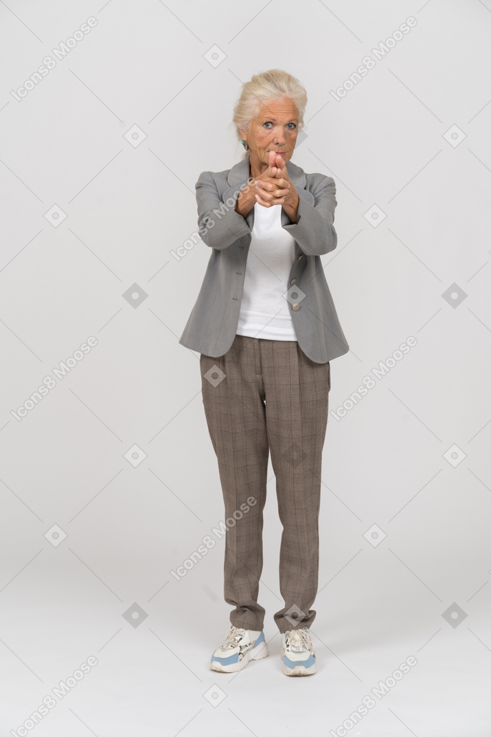 Front view of an old lady in suit showing gun with fingers