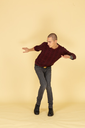 赤いプルオーバーで踊っている若い男の正面図