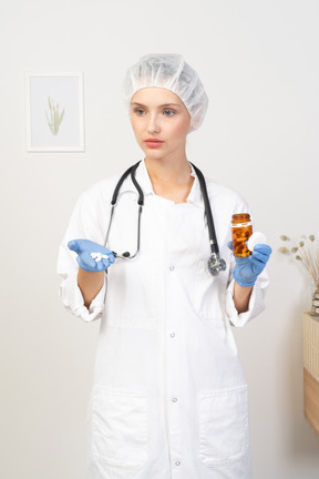 拿着药片的一位年轻女性医生的正面图