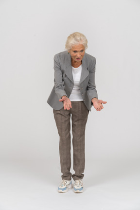 Vista frontal de una anciana en traje agachándose y explicando algo