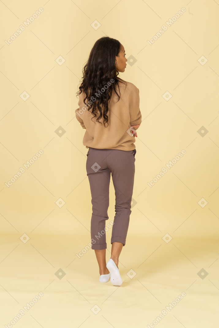 Vista posterior de una mujer joven de piel oscura tomados de la mano sobre el estómago