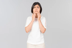 Preoccupied looking young indian woman touching her face
