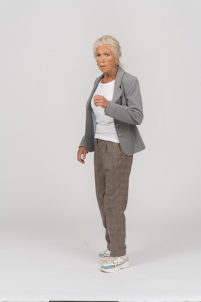 Vista frontal de una anciana impresionada en traje mirando a la cámara