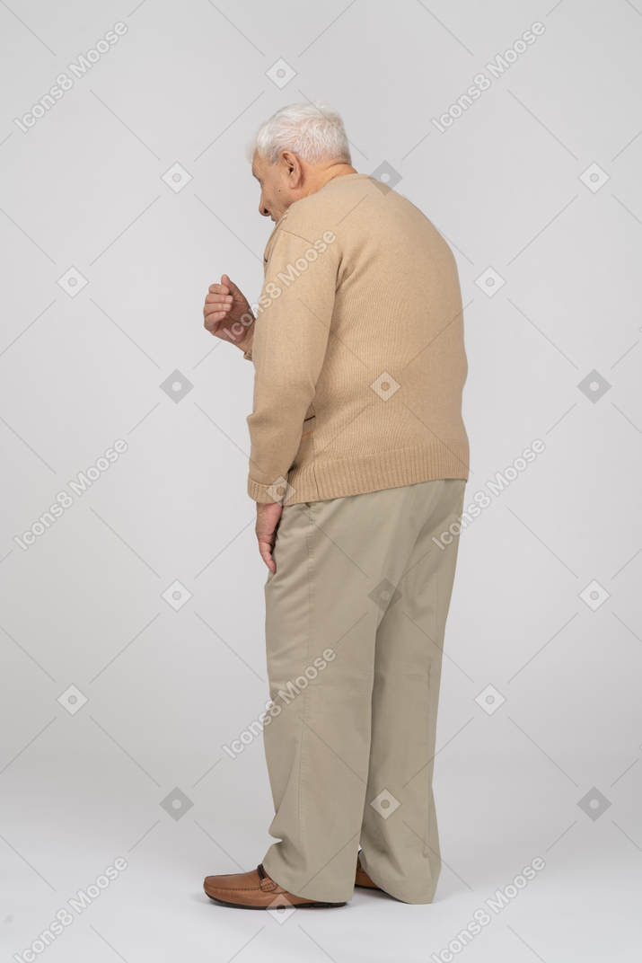 Vista lateral de un anciano con ropa informal explicando algo